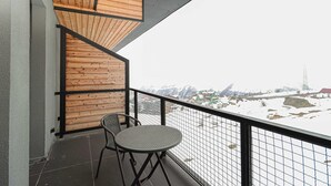 A balcony with a view of a snowy landscape, wooden paneling, and two chairs. - Cozy & Family-friendly Apt. in Gudauri - by Wehost (Gudauri)