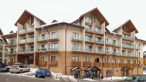 A multi-story hotel with balconies, a ski shop, and a ski lift visible in the background. - Charming New Gudauri Studio - by Wehost (Gudauri)