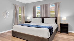 Een moderne slaapkamer met een groot bed, twee nachtkastjes en een raam met gordijnen.
