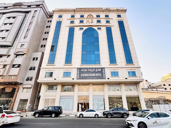 A hotel with a prominent entrance, large windows, and a sign indicating it is the Alryada Grand Hotel. - alryada grand (Makkah)