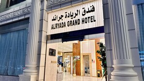 The exterior of Alryada Grand Hotel with a modern facade, large entrance doors, and a sign in both Arabic and English. - alryada grand (Makkah)