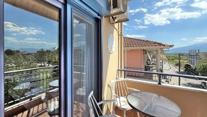 Ein Balkon mit Glastür, Tisch und zwei Stühlen.
