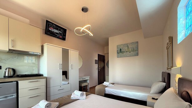 Ein Hotelzimmer mit Bett, Schreibtisch, Küchenzeile und Fernseher.