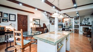 Una cocina amplia con una isla central, sillas de madera, una mesa de comedor y una escalera que conduce a un nivel superior.