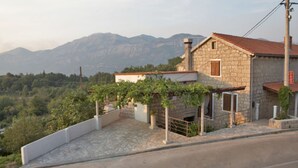 Una casa de piedra con techo de tejas rojas, una escalera de piedra y un viñedo.