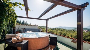 Un jacuzzi con mobiliario de mimbre y vistas a un paisaje montañoso.