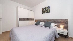 A bedroom with a bed, a nightstand, a wall-mounted artwork, and a sliding door closet. - Star house 3 (Novalja)