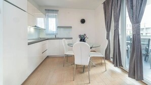 A modern kitchen with white cabinets, a glass dining table, and a window with curtains. - Star house 3 (Novalja)