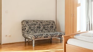 Ein Zimmer mit einem zebra-gemusterten Sessel, einem Holzschrank und einem Bett mit weißer Bettwäsche.