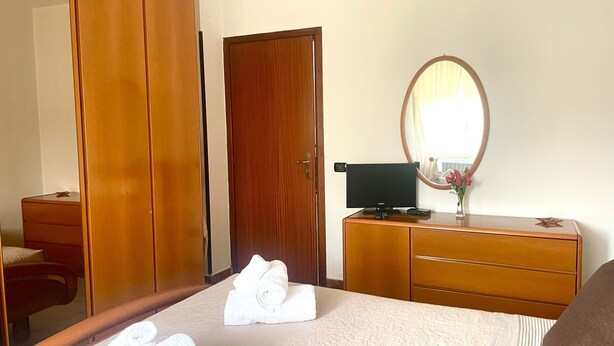 Ein Hotelzimmer mit einem Bett, einem Holzschrank, einem Schreibtisch mit Computer und einem Spiegel.