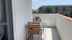 Ein Balkon mit Tisch und Stühlen, einer Blumenvase und Blick auf ein Baugerüst.
