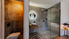 Une salle de bain moderne avec une douche à parois de verre, un miroir rond, un meuble-lavabo en bois et des toilettes.