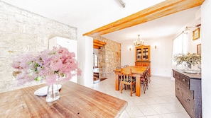 A dining area with a wooden table, chairs, a cabinet, and a stone wall.