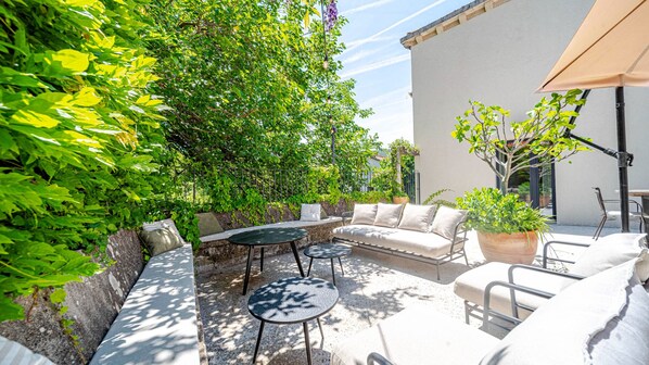 Un patio al aire libre con un sofá, dos mesas redondas y una planta en maceta.