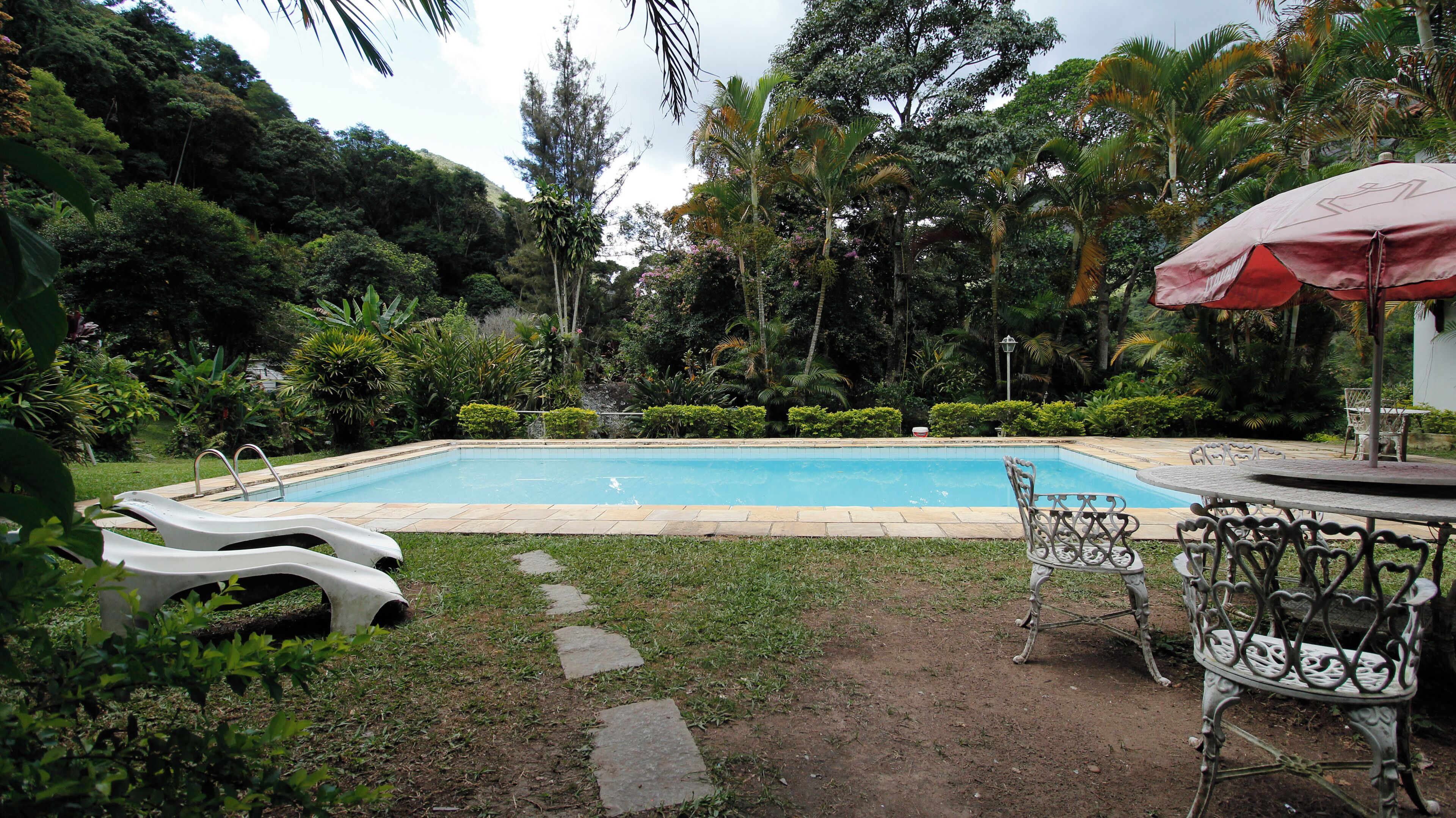 Una piscina al aire libre, sombrillas, sillones reclinables de piscina