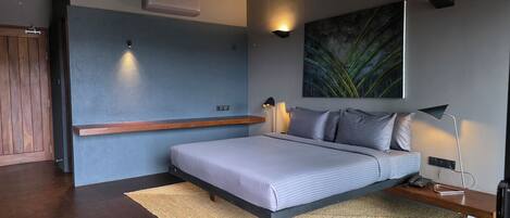 A modern bedroom with a bed, bedside lamp, and a wall-mounted air conditioner.