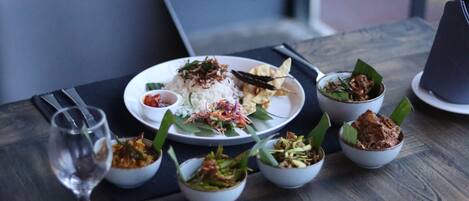 A dining table with a plate of food, including rice, vegetables, and a small bowl of sauce.