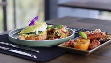 A plate of food with avocado toast and a salad, and a small dish with roasted vegetables.