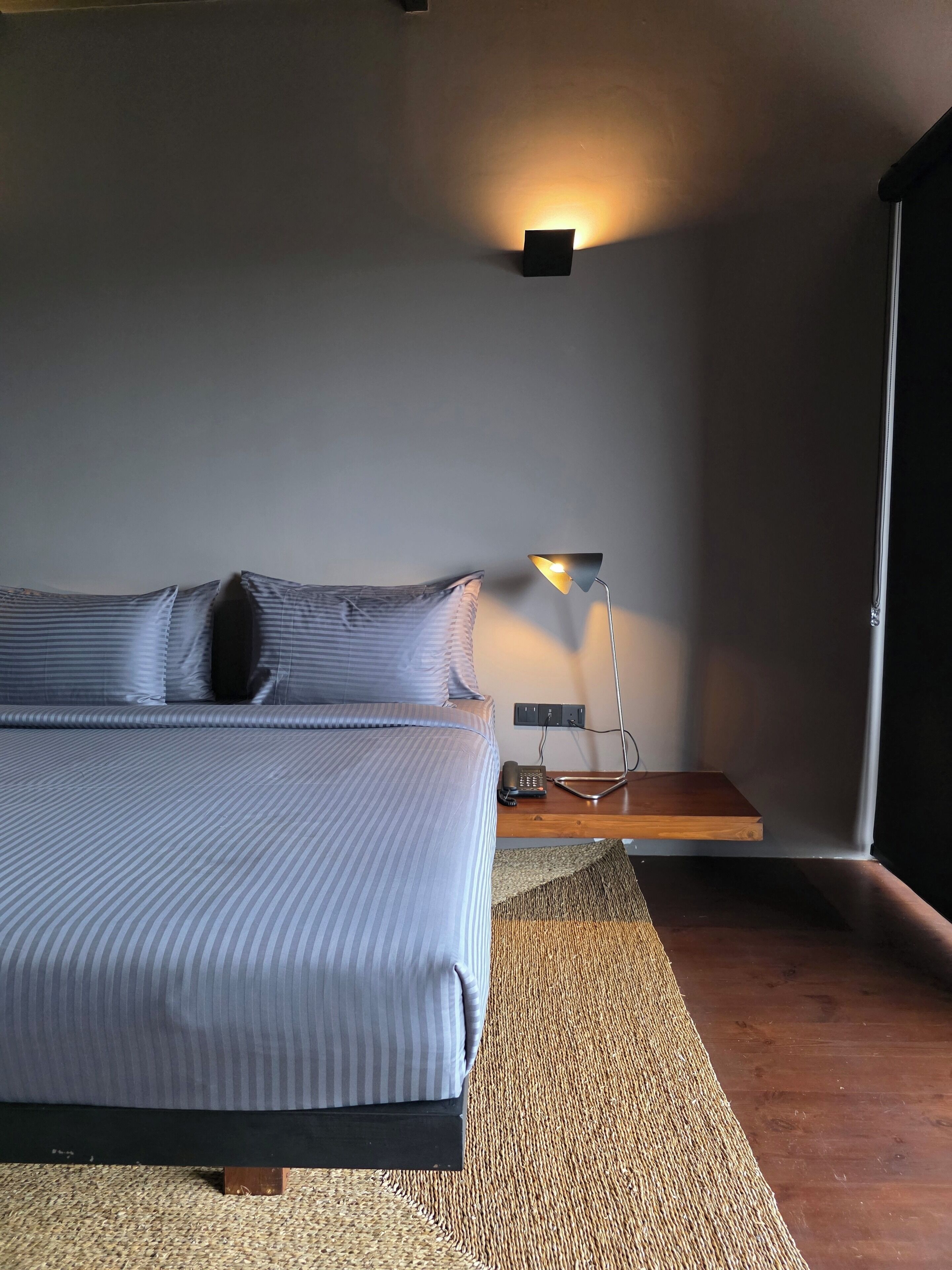 Une chambre à coucher moderne avec un grand lit, une lampe de chevet et une petite table sur laquelle se trouve un téléphone.