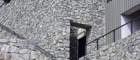 A stone staircase leading to a building with a metal railing and a window.
