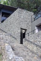Una escalera de piedra que conduce a un edificio con barandilla de metal y una ventana.