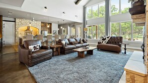 Ein geräumiges Wohnzimmer mit Ledersofas, einem Couchtisch und einem Kamin aus Stein.