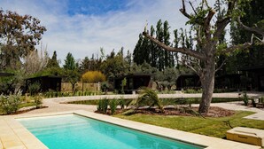 A swimming pool surrounded by a landscaped garden with various trees and shrubs. - Lun Lodges (Chacras de Coria)