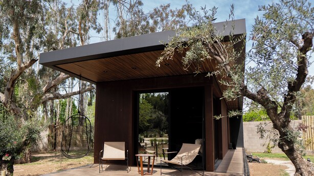 A modern outdoor patio with a wooden deck, two lounge chairs, and a hanging chair. - Lun Lodges (Chacras de Coria)