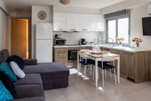 A modern kitchen with white cabinets, a microwave, and a dining area with a table and chairs.