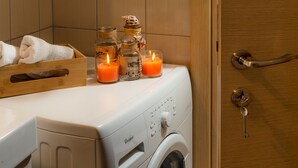 Una lavadora de carga frontal con panel de control, un tendedero de madera y tres velas encendidas encima.