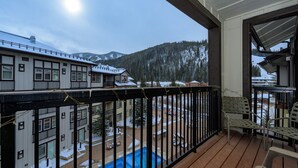 A balcony with a view of a swimming pool, snow-covered ground, and buildings in the background. - Founders Pointe 4649 Ski Mountain Condo Resort Amenities Walk to Ski Lifts (Winter Park)