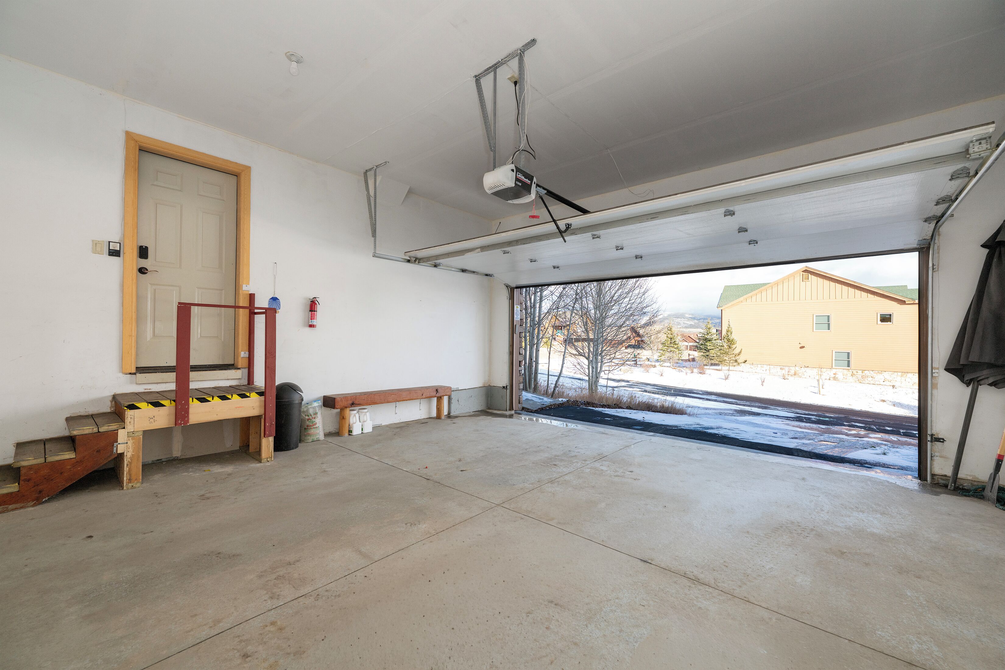Spacious garage with convenient storage and winter views of the neighborhood through the open door.