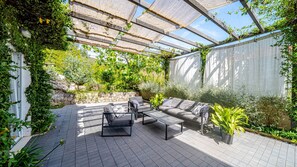 Eine Terrasse im Freien mit einer Sofagarnitur, einem Couchtisch und Topfpflanzen.
