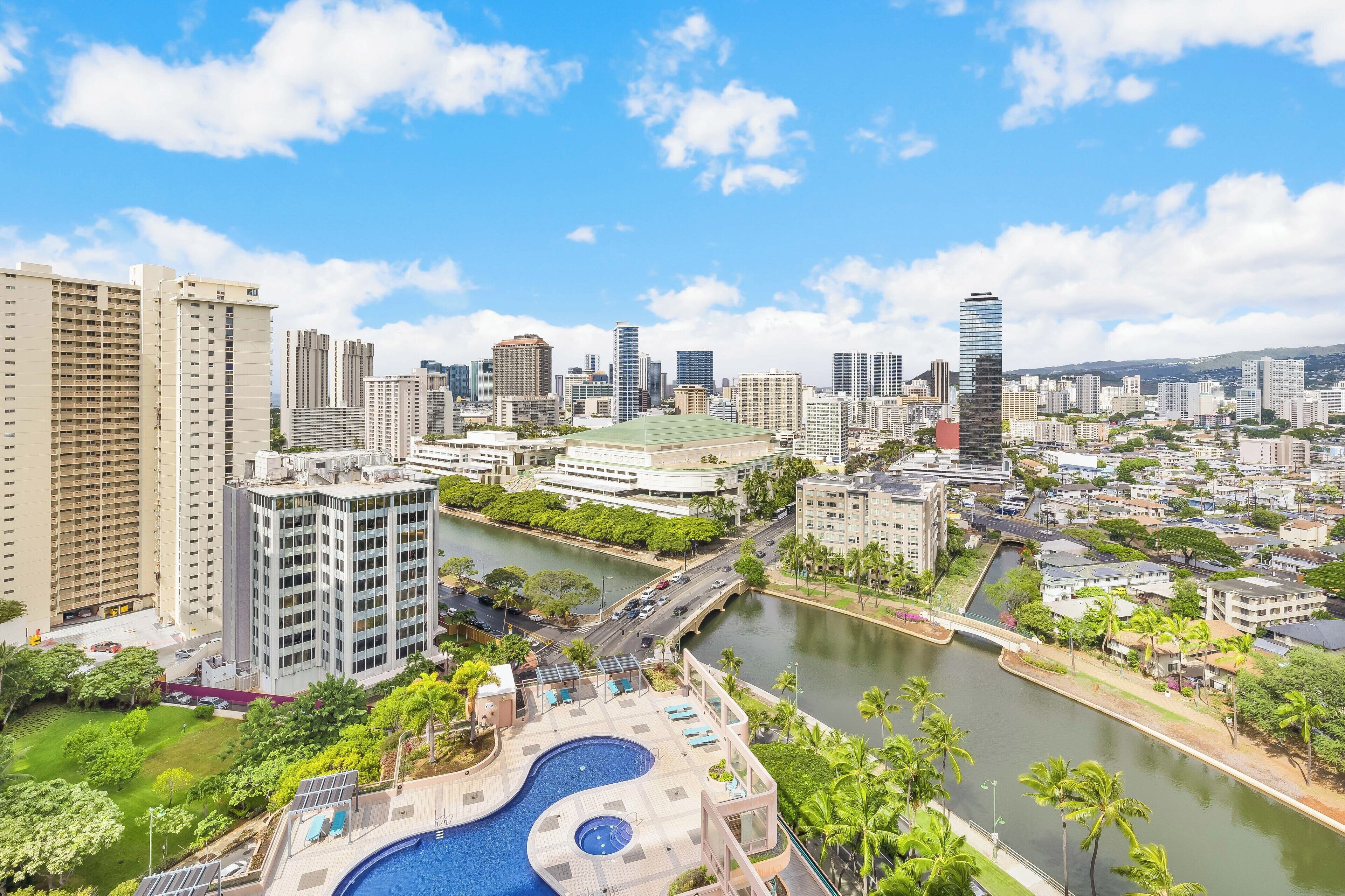 A cityscape with high-rise buildings, a river, and a swimming pool area.