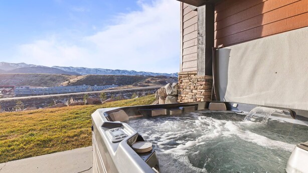 Un jacuzzi con vistas a montañas y un edificio al fondo.
