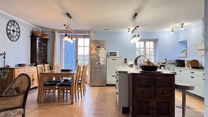Cucina spaziosa con isola centrale, zona pranzo con sedie in legno e un'ampia finestra che offre luce naturale.