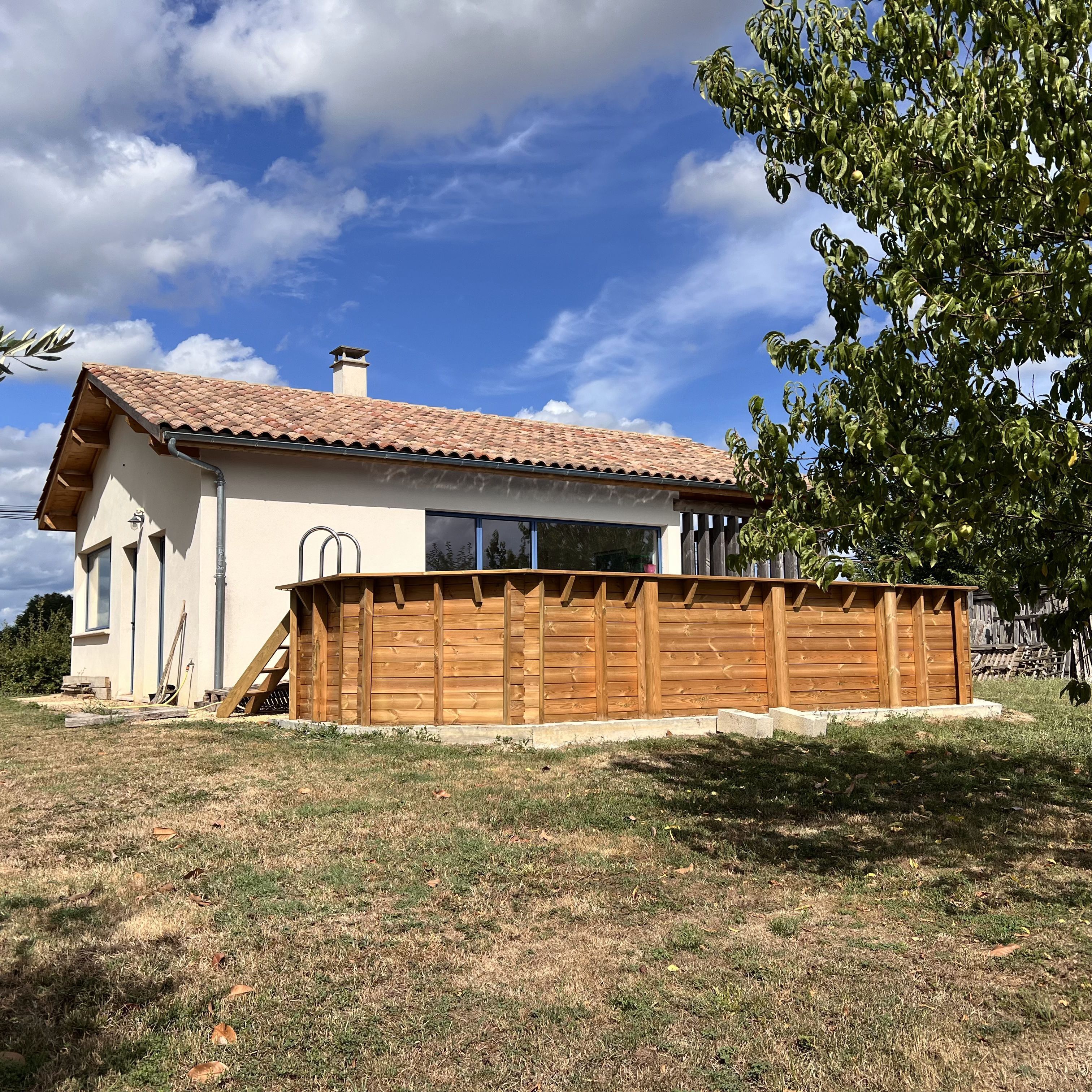 A house with a tiled roof, a wooden fence, and a grassy yard.