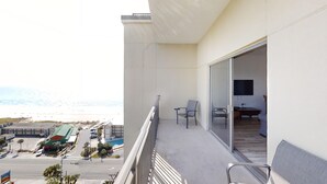 Un balcón con vista a la playa, una silla y una mesa.