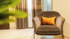 A modern armchair with a single cushion, positioned in a room with a light-colored floor and a door in the background. - Fully furnished and spacious 2bedroom House in Accra (Nii Okaiman East)