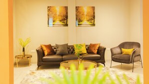 A modern living room with a sofa, armchair, coffee table, and two paintings on the wall. - Fully furnished and spacious 2bedroom House in Accra (Nii Okaiman East)
