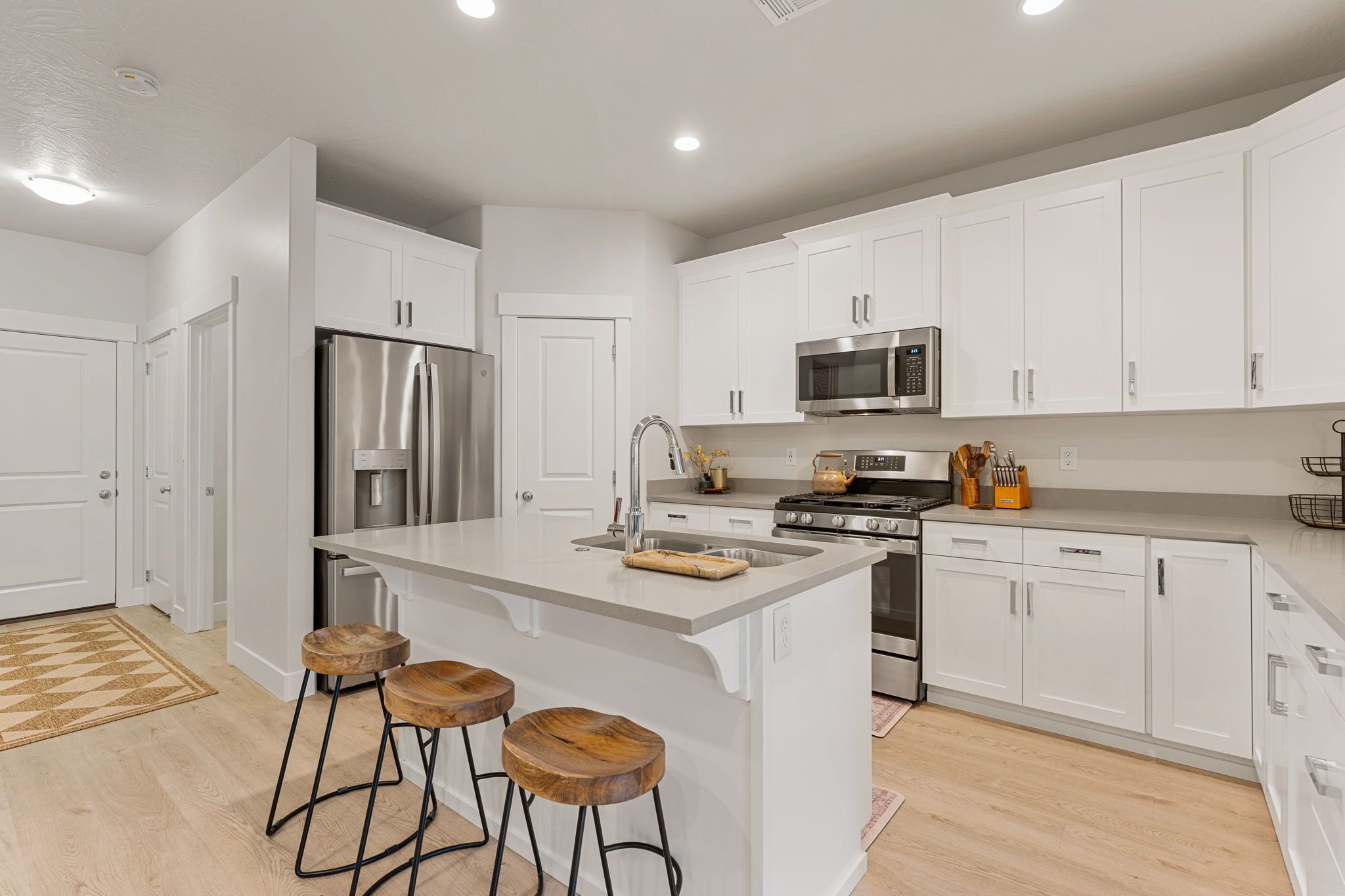 A modern kitchen with white cabinets, stainless steel appliances, and a central island with stools.