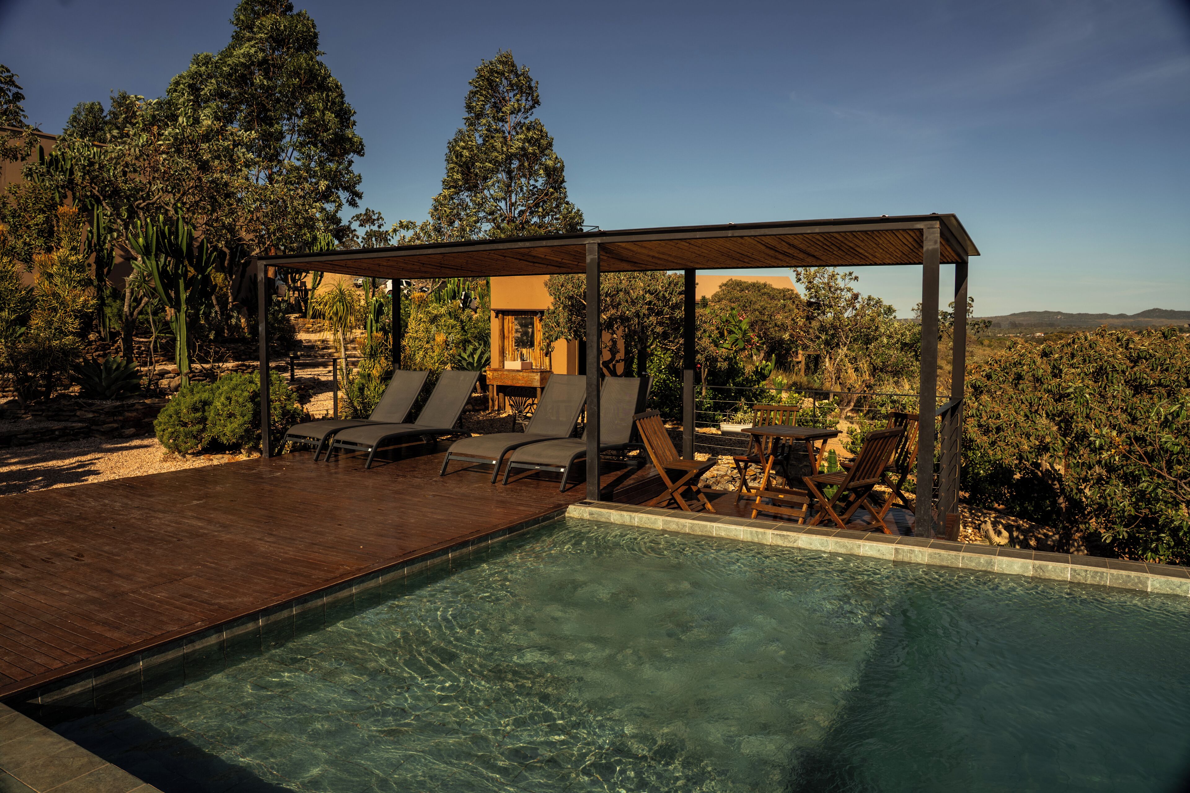 A pool area with a wooden deck, lounge chairs, and a covered seating area.