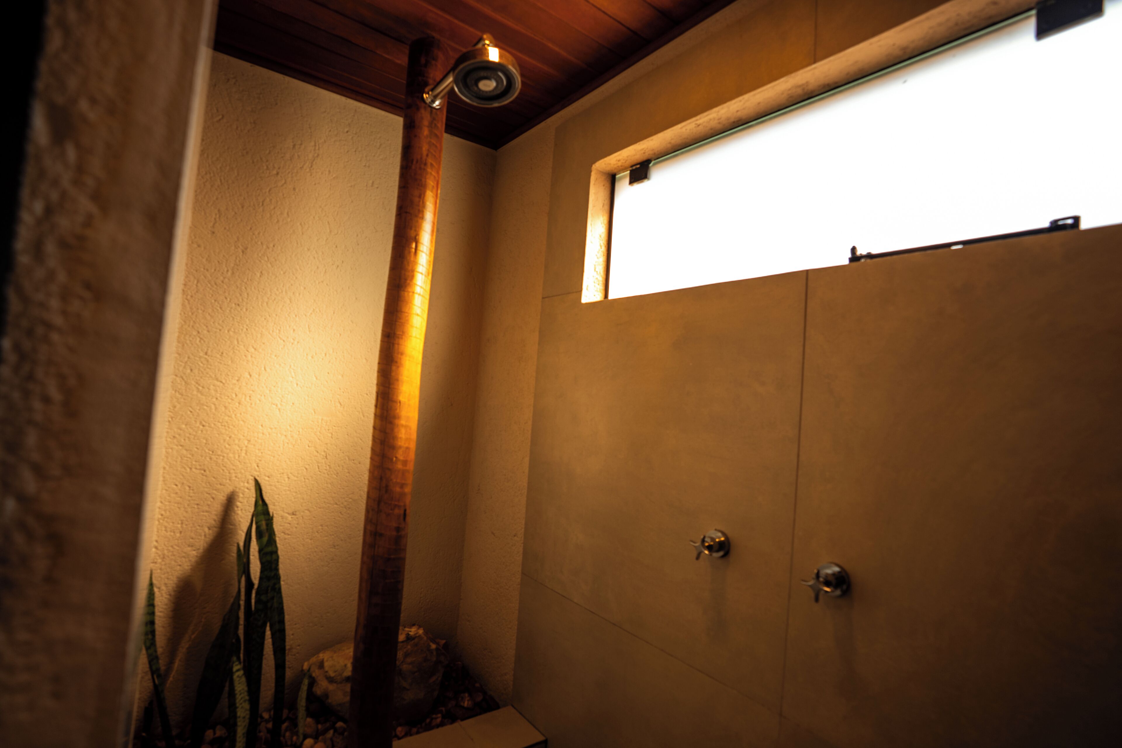 A bathroom with a shower, a window, and a wooden beam.