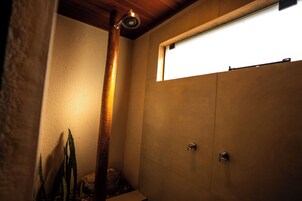 A bathroom with a shower, a window, and a wooden beam.