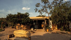 Un espacio al aire libre rústico con un banco de madera, rodeado de grava, bajo un cielo despejado.