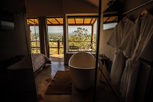 Quarto com cama, uma banheira grande e vista para o exterior.