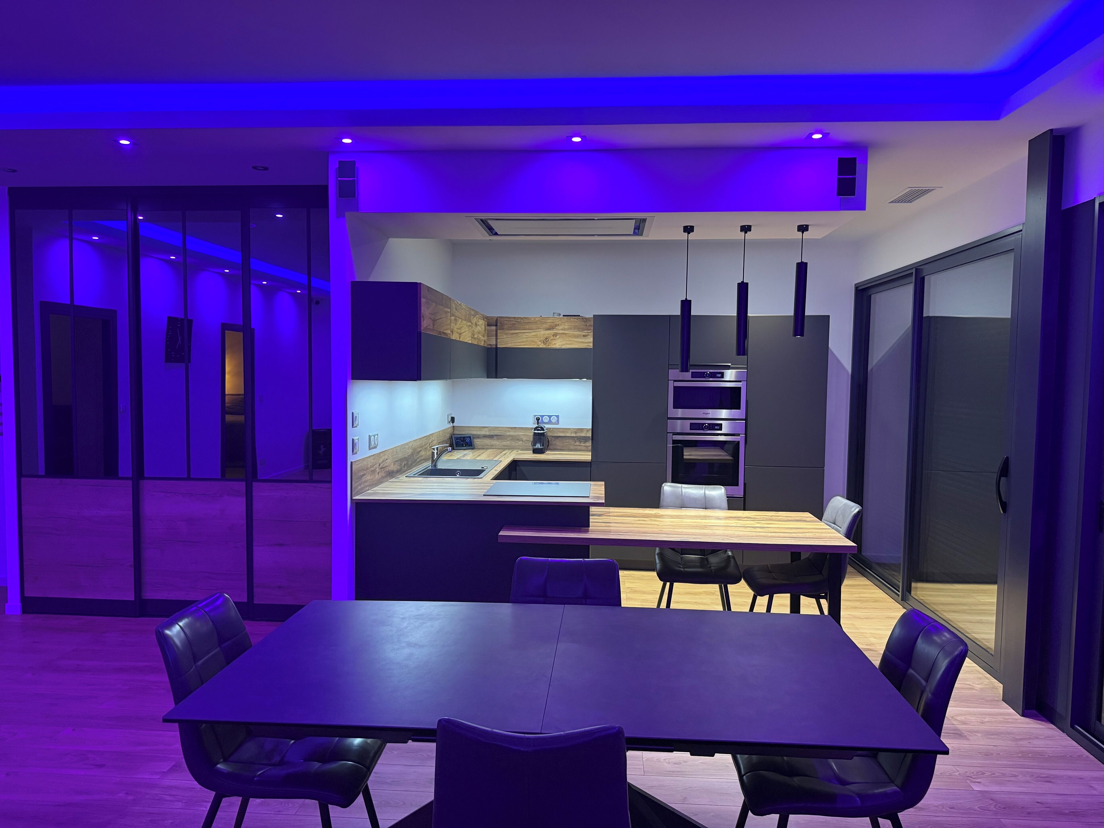 Una cucina moderna con isola centrale, forno integrato e illuminazione a sospensione.