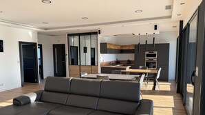 A modern living room with a grey sofa, a dining area with a table and chairs, and a kitchen with dark cabinets and a wooden countertop. - Magnificent luxury loft with top-of-the-range amenities. (Montussan)