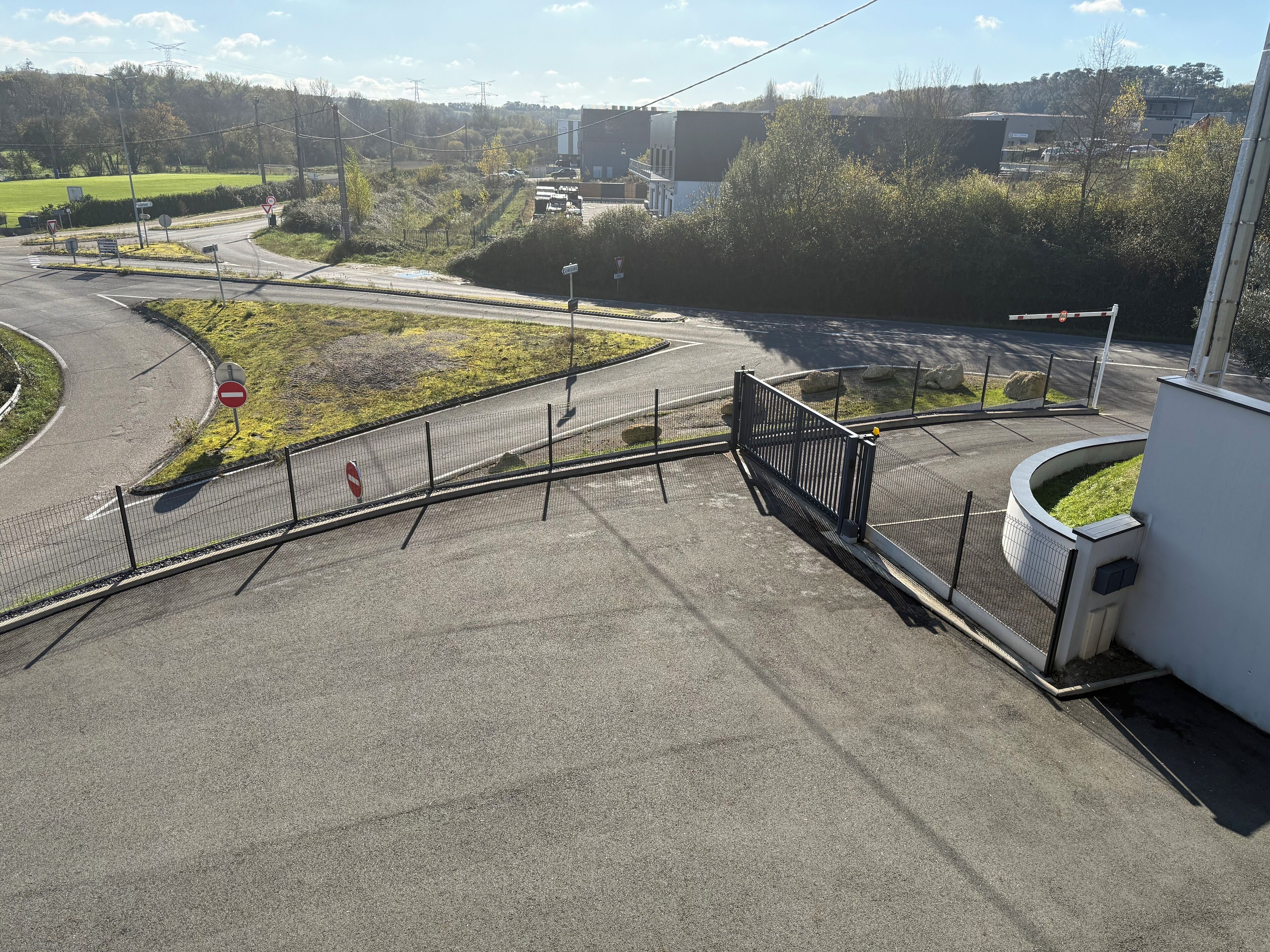 A road intersection with a no-entry sign, a pedestrian crossing, and a metal fence.