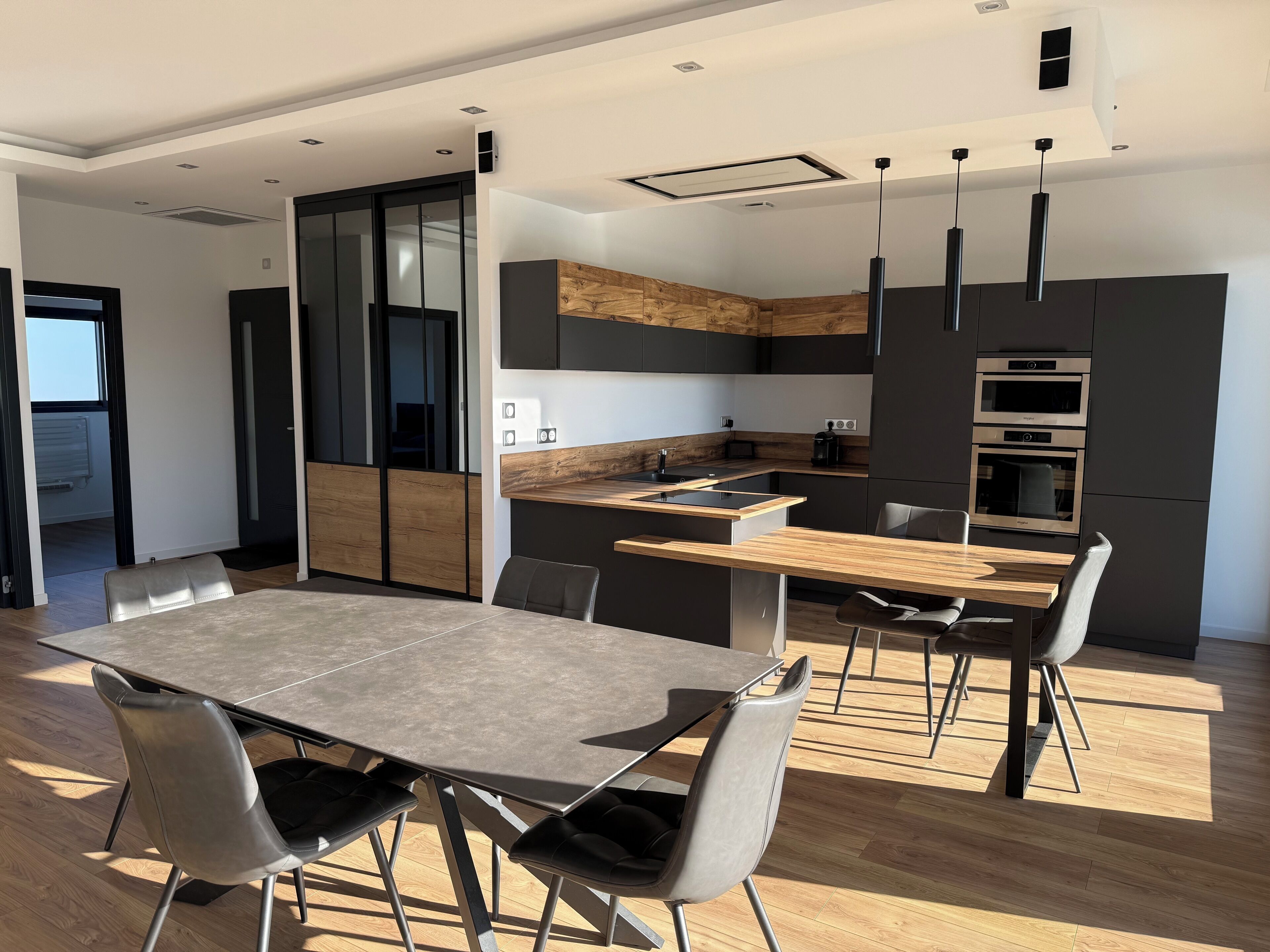 A modern kitchen with a central island, dark cabinetry, and built-in appliances.